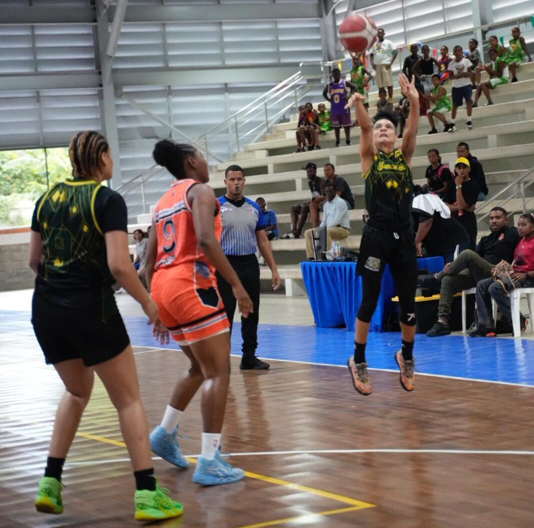 Jennifer Jiménez, del club San Carlos, realiza un lance de tres sobre la defensa de Angie Hodge, de La Ciénaga. Observa, a la izquierda, Tawni Olivero.